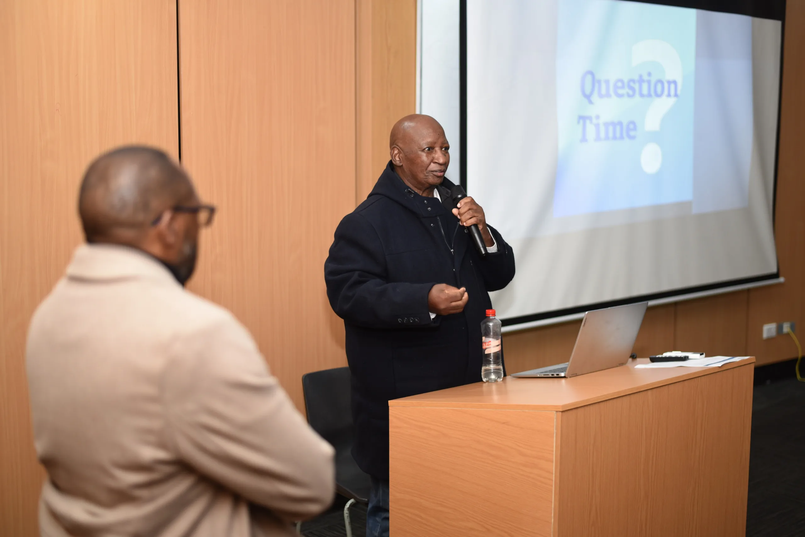 Dr Teboho Pitso delivering a lecture at VUT on neo-coloniality and cyber-coloniality in education, with students and staff engaging in discussion.