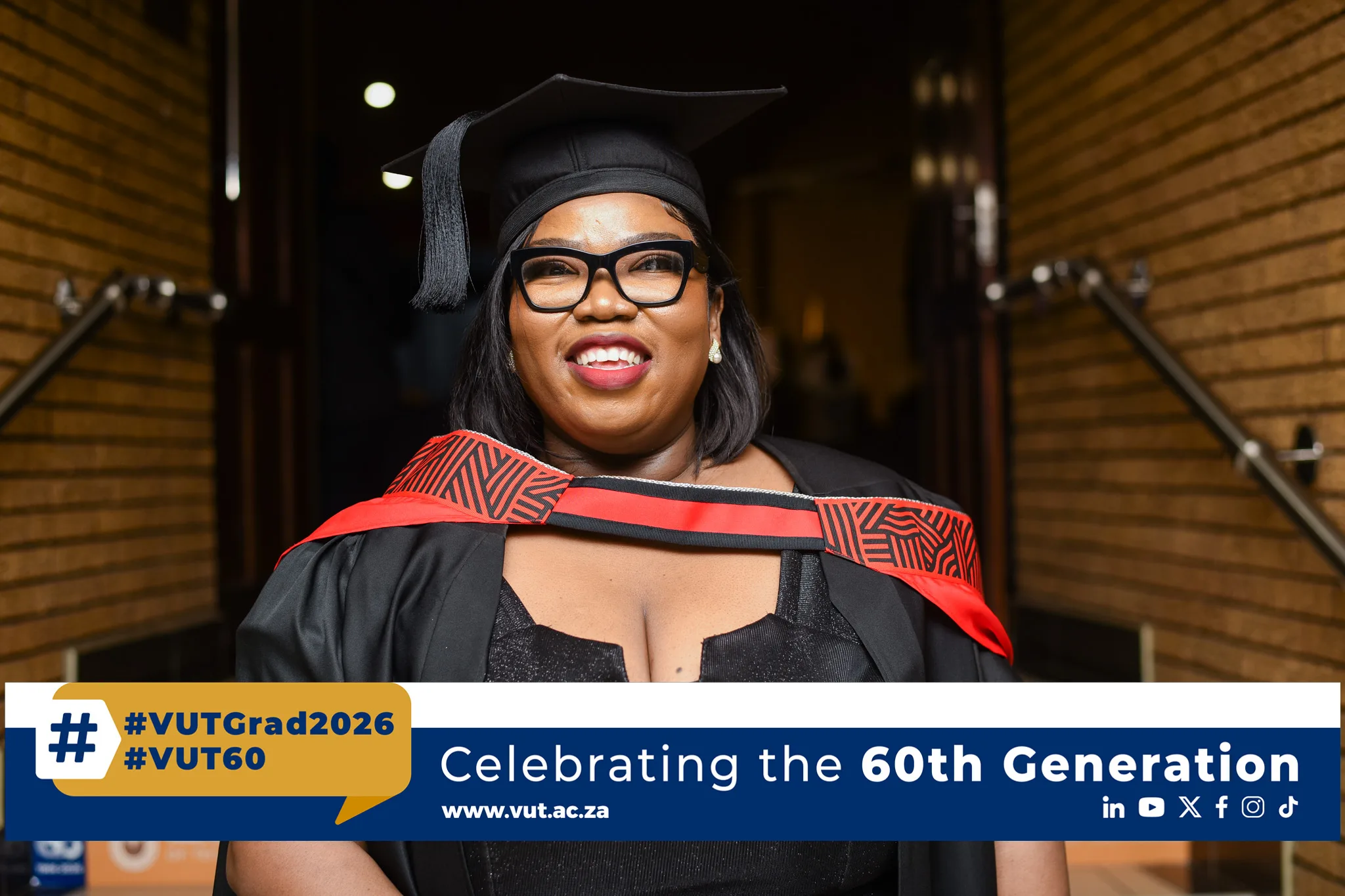 Smiling graduate in black cap and gown with tassel, standing in a brick hallway; banner at bottom reads 'Celebrating the 60th Generation'.