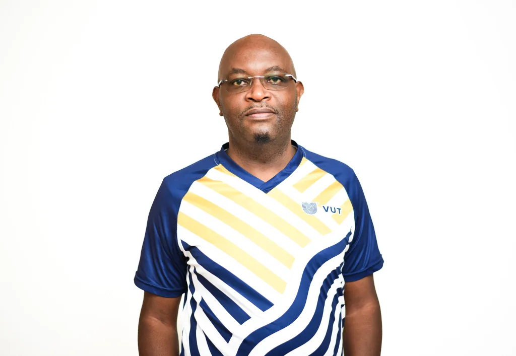 Portrait of a man wearing a blue and white striped sports jersey with yellow chevrons and a VUT logo, facing the camera.