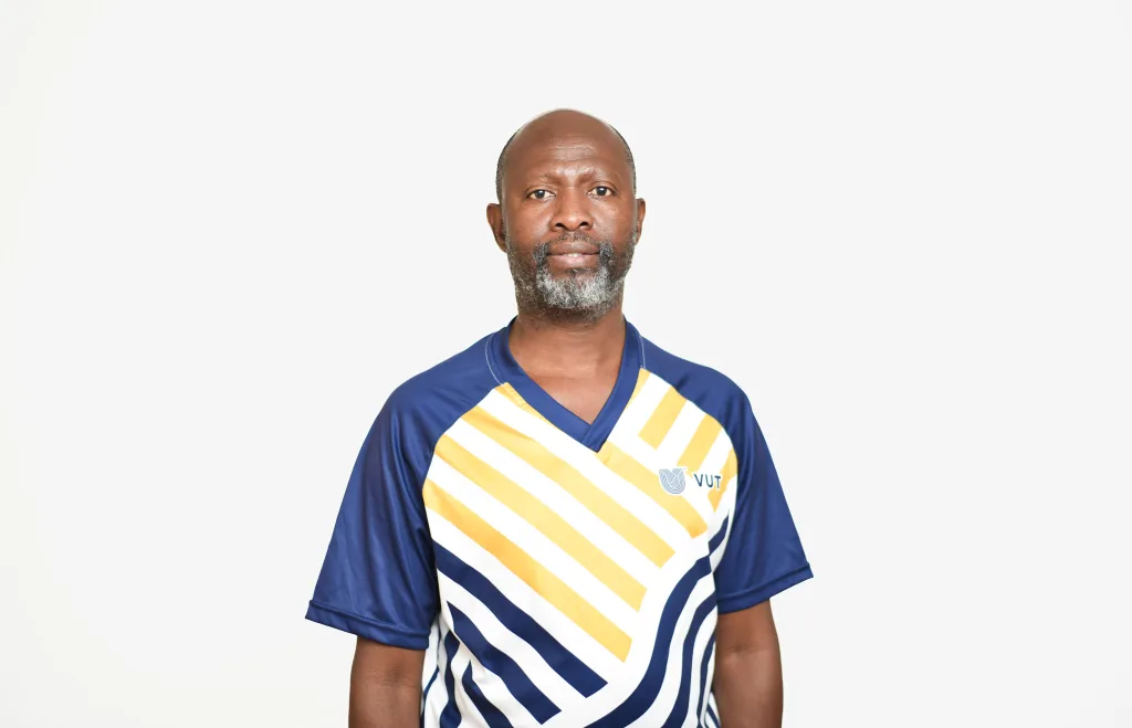 Adult man wearing a blue and white striped sports jersey with yellow accents, looking at the camera against a light background.
