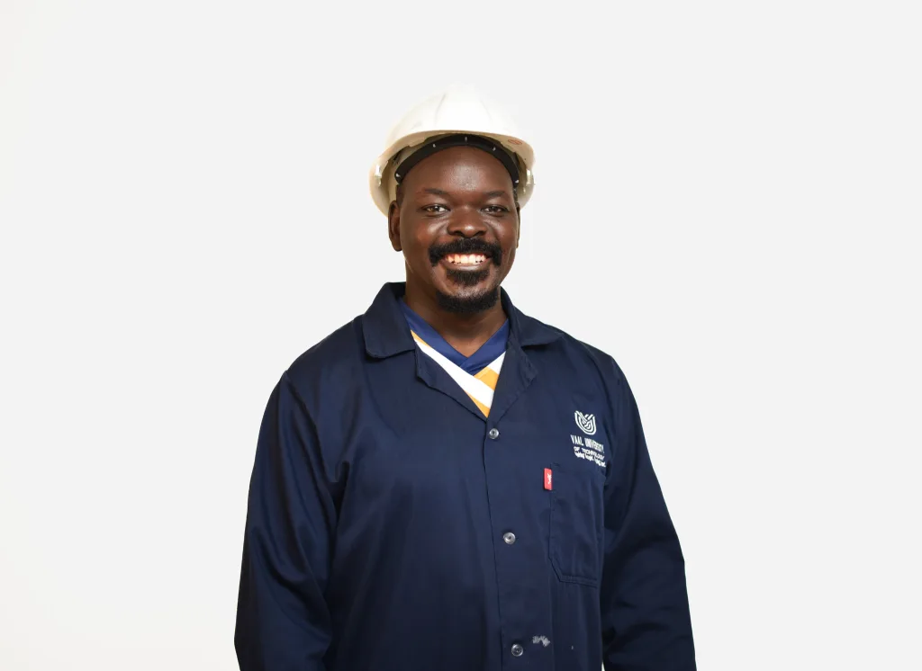 Smiling construction worker wearing a white hard hat and navy coveralls against a white background.