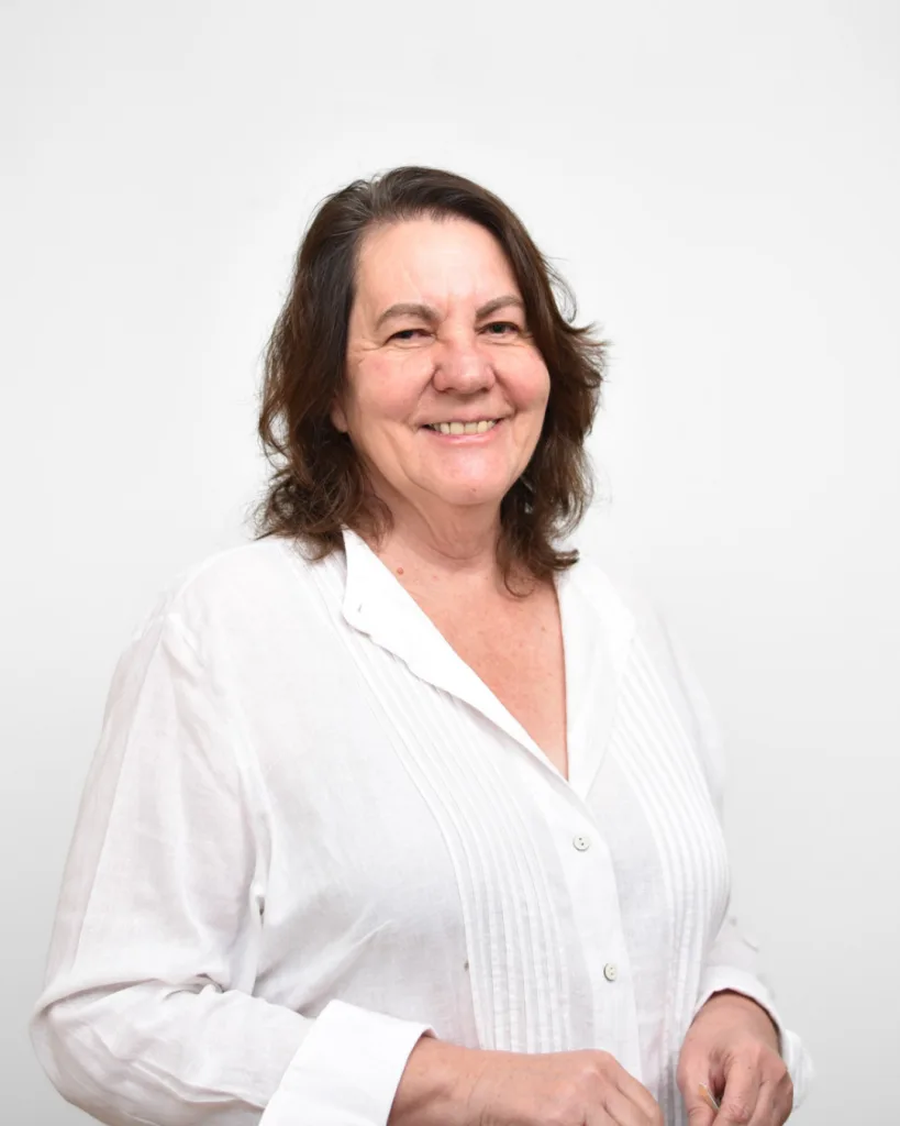 Smiling woman with shoulder-length brown hair in a white button-down shirt, posing against a plain white background (portrait].