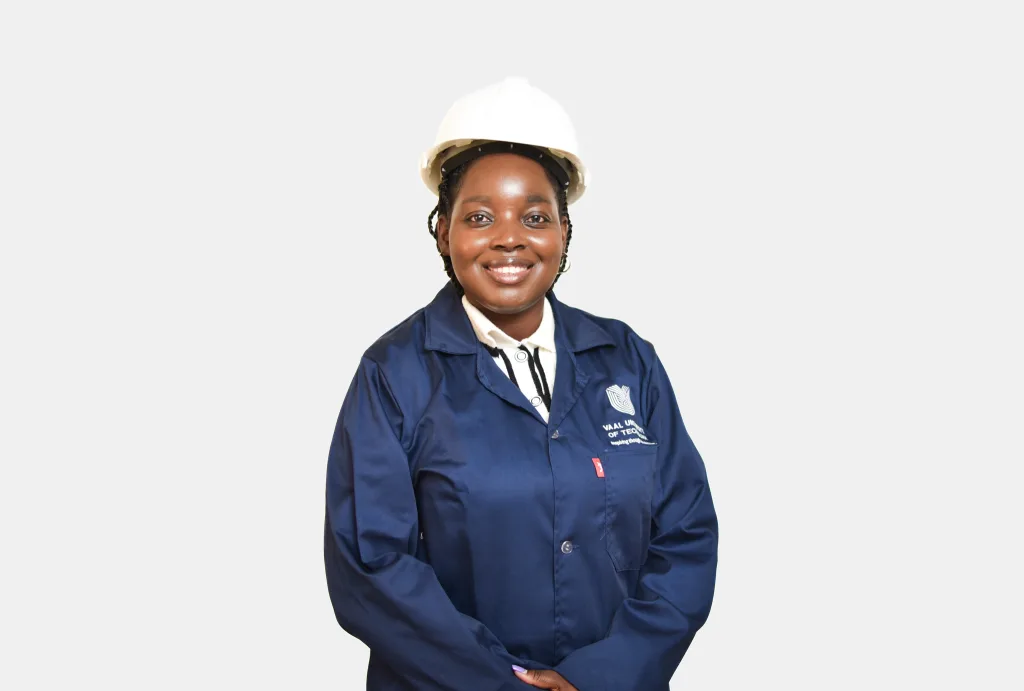 Smiling woman in a white hard hat and navy blue work uniform, posing against a light background.