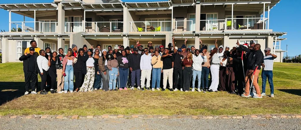 VUT Staff members – Vaal University of Technology Large diverse group posing for a photo on a lawn in front of a two-story building with balconies.