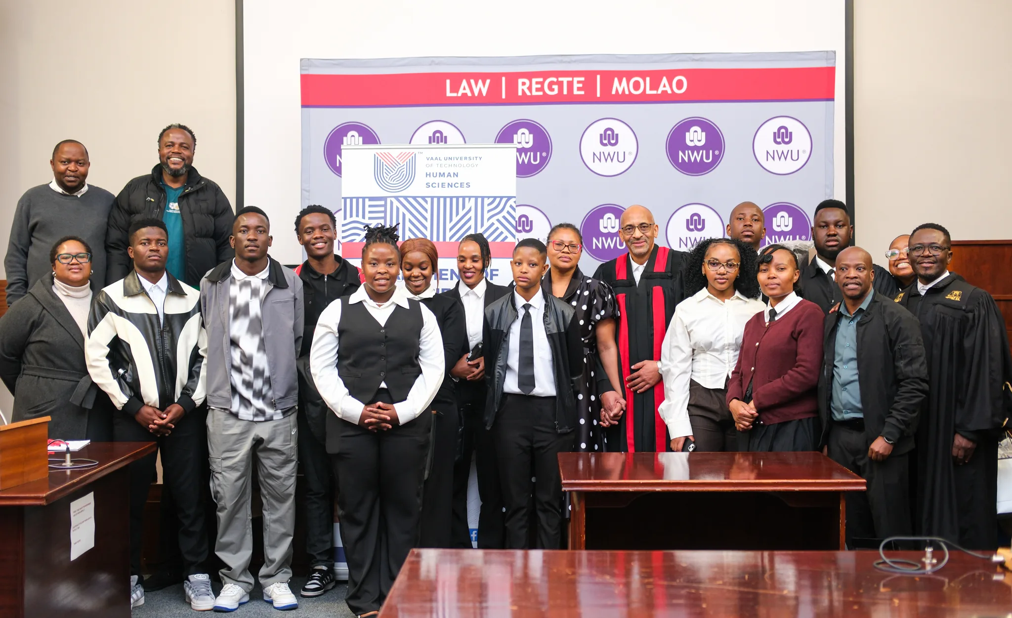 Moot court – Vaal University of Technology – Vaal University of Technology Group photo of a diverse group of students and faculty in robes and formal attire posing in a room with a Law banner and NWU logos in the background.
