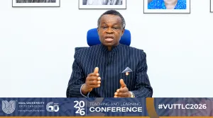 Prof Lumumba 2 – Vaal University of Technology – Vaal University of Technology Man in a dark pinstriped suit speaks at a conference, with a Vaal University of Technology banner reading 'Teaching and Learning Conference 2026' at the bottom.