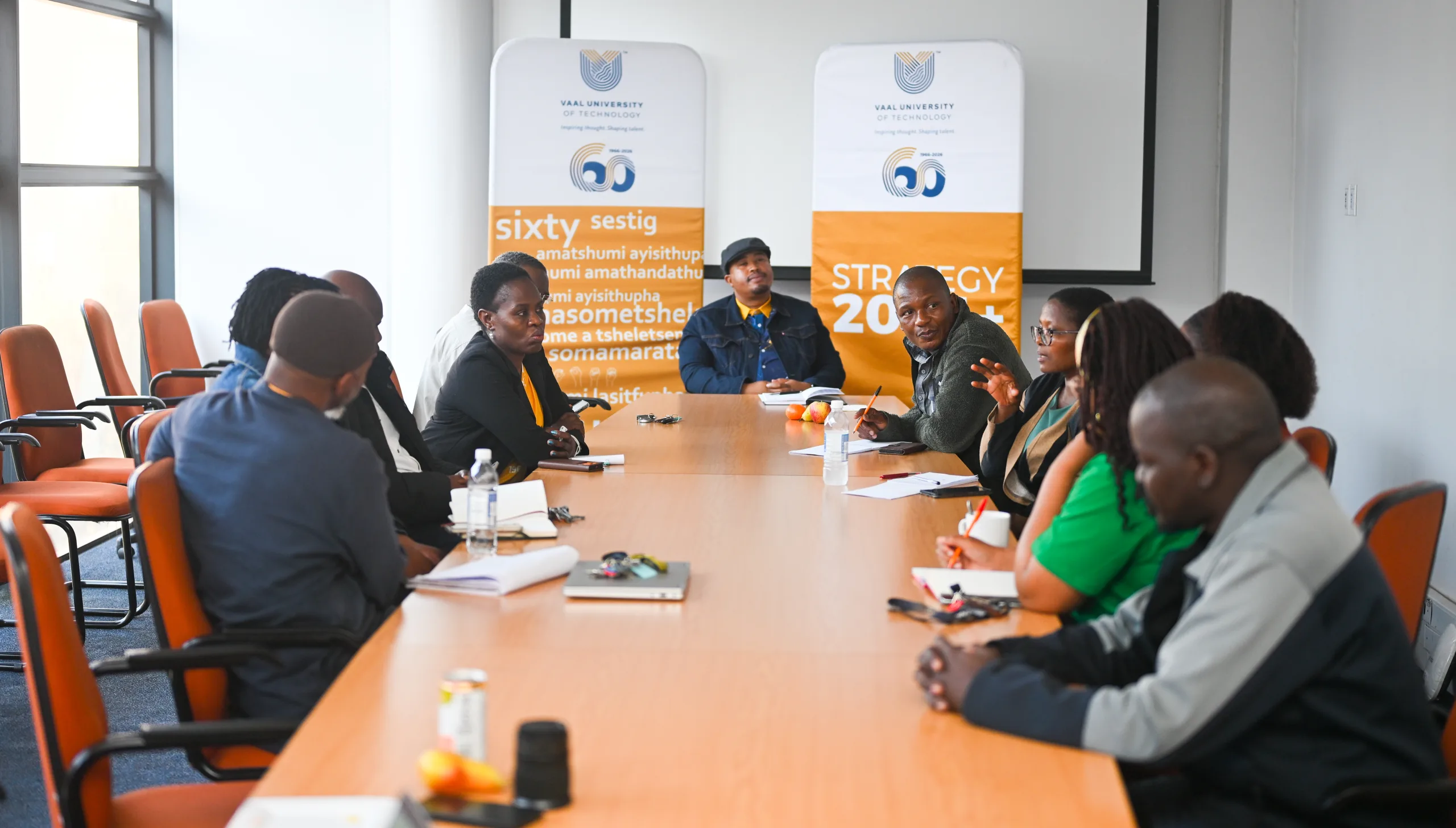 FET conducts ECSA Mock audit ahead of 2027 accreditation visit – Vaal University of Technology – Vaal University of Technology Diverse group of professionals seated around a long conference table in a meeting room, orange banners for Vaal University in the background.