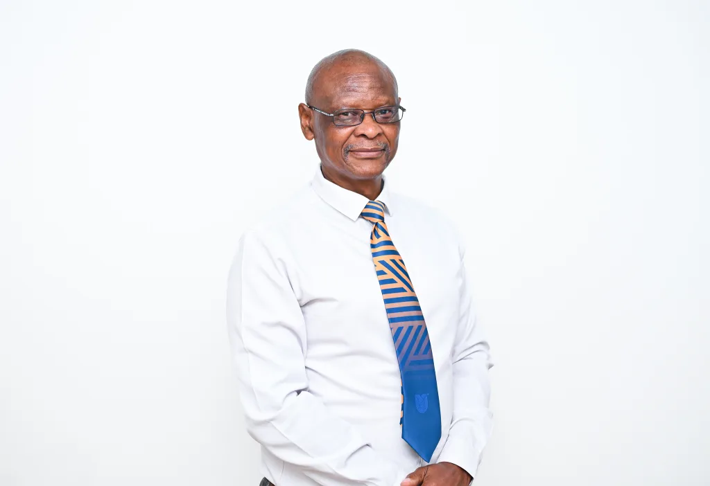 Portrait of a man in a white shirt with an orange-and-blue striped tie, wearing glasses, against a plain white background.
