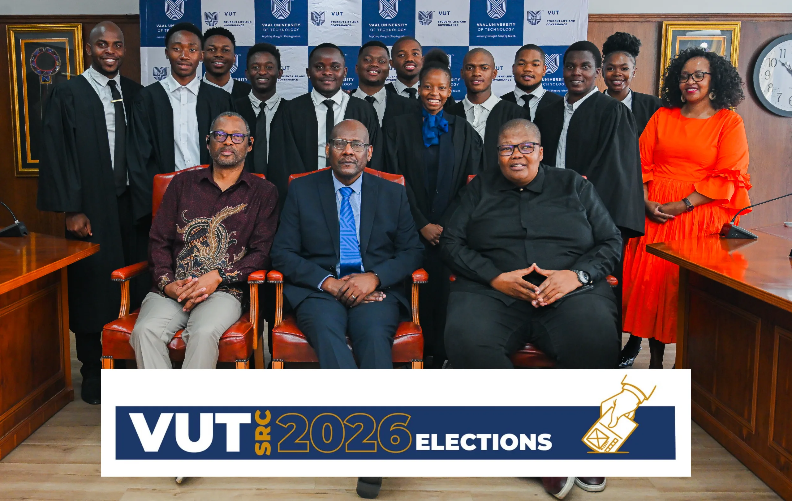 Group of graduates in black gowns pose with two officials in front of a banner that reads VUT SRC 2026 Elections.